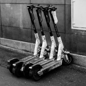 A group of electric scooters parked against a building wall, highlighting urban transportation.